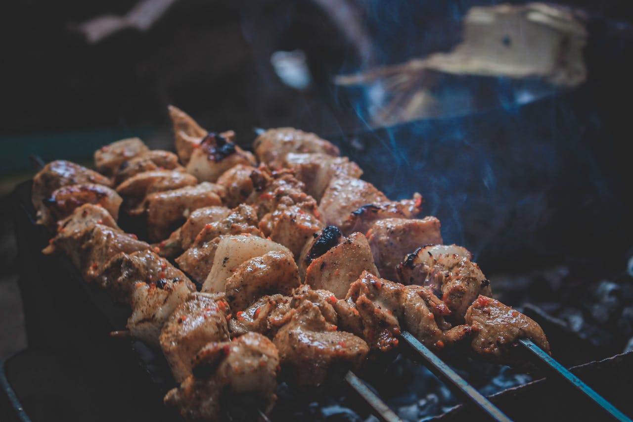 Delicious grilled skewers sizzling on a charcoal grill with smoke and juicy texture.